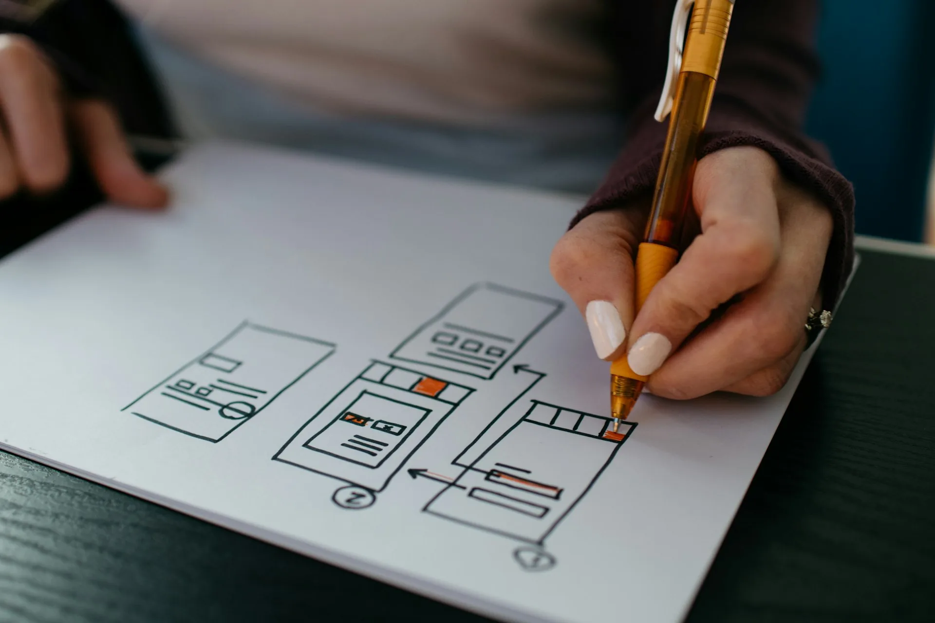 Discovery phase — hand sketching wireframes on paper with an orange pen